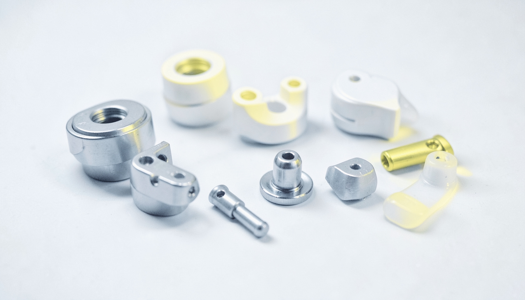 Clean white and pale-blue duotone photograph of precision-machined medical components arranged on a sterile surface.